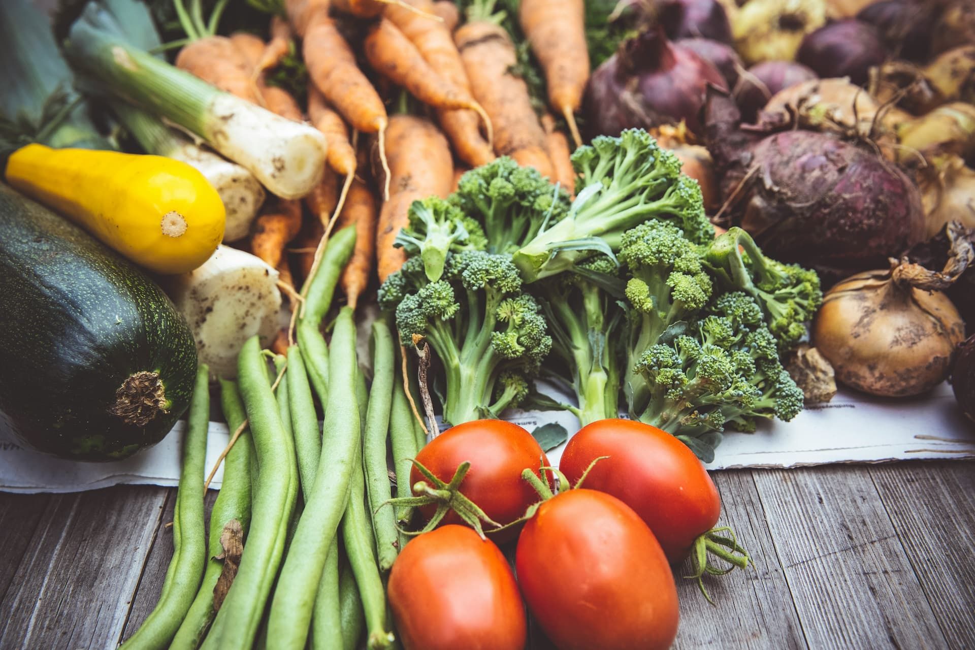 Des légumes, tomates, haricots verts, courgettes, poireaux, oignons et betteraves posés sur une table